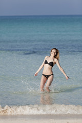 Fototapeta na wymiar Frau mit Bikini springt im meer hochformat