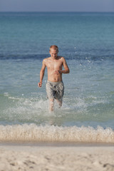 Fototapeta na wymiar mann rennt am strand im Wasser Hochformat