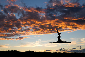 female gymnast jumping in sunset