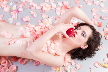 Obraz na płótnie Canvas beautiful nude woman with roses eating an apple