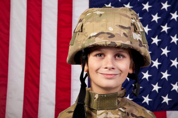 Boy USA soldier in front of American flag.