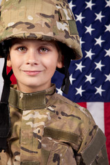 Boy USA soldier in front of American flag.