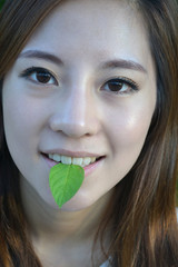 Beautiful young asian women with a leaf in mouth