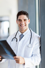 smiling young male doctor holding CT scan film in hospital