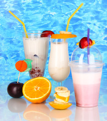 Delicious milk shakes with fruit on blue sea background