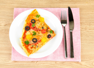 plate with a slice of delicious pizza on wooden background