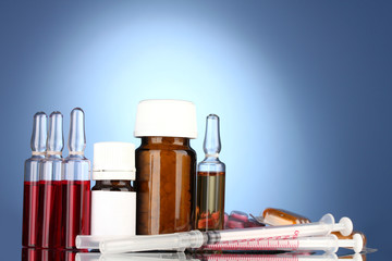 medical ampules, bottles, pills and syringes on blue background