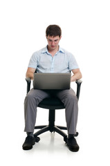 The businessman sits in an armchair with laptop