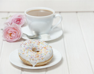 a doughnut and a cup of tea on white table