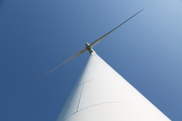 Looking upward to a big wind turbine and a blue sky