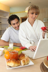 Couple using laptop at breakfast