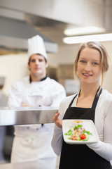 Smiling waitress presenting salmon dish