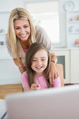 Fototapeta na wymiar Mała dziewczynka, wskazując na laptopa i śmiejąc się z matką