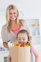 Daughter looking into grocery bag with mother watching
