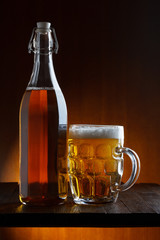Beer bottle and mug on wooden table still life