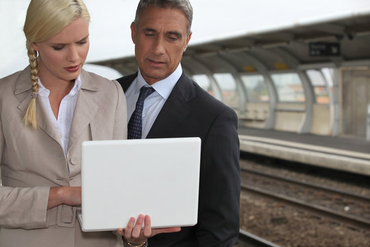 Business couple with a laptop on a railway platform