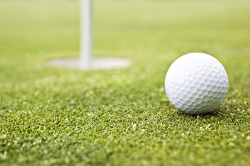Golf ball on a putting green with the flag in background