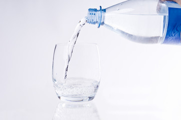 Wasserflasche beim Eingießen von Wasser in ein Glas