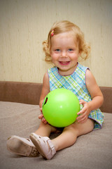 Fototapeta premium The little blond smiling baby girl with ball