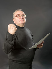 Elderly the man looks in top and shows a fist