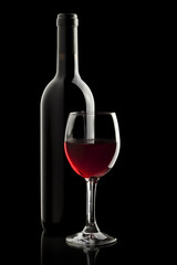 Elegant red wine glass and a wine bottle in black background