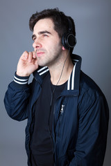 Smiling young casual man listening to music with headphones