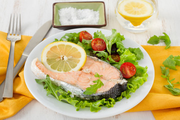boiled salmon with lemon and salad on the plate
