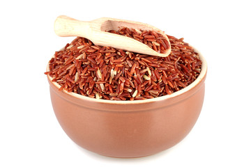 red rice in a brown  platewith a wooden scoop  , isolated