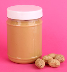Delicious peanut butter in jar of peanut near on pink