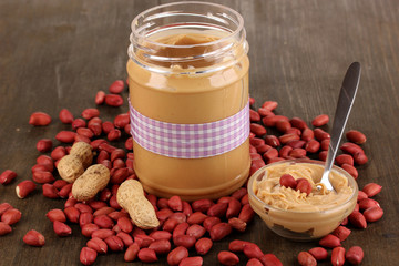 Delicious peanut butter in jar on wooden table close-up