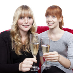 young beautiful blond and red haired girls with champagne on red