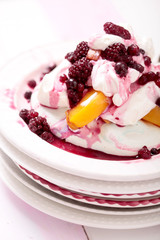 Pavlova mit Sahnefüllung Pfirsichen und roten Beeren