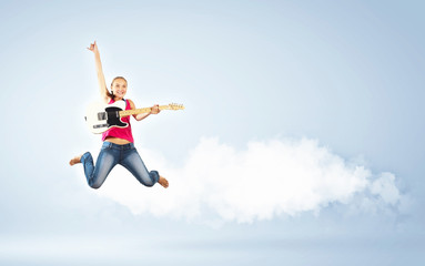 young woman playing on electro guitar and jumping