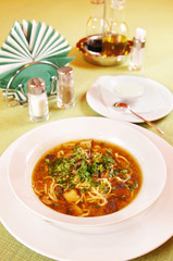 Soup with noodles and mushrooms on a laid table