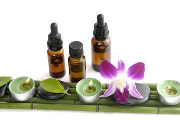 massage oil with stones and candle with orchid (spa concept)