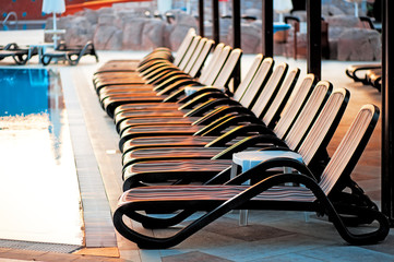 Several of sun loungers by the pool at sunrise.