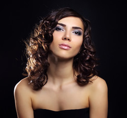 Sexy young woman with curly hair on black background