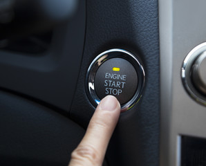 finger pressing the Engine start stop button of a car - obrazy, fototapety, plakaty