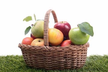 wicker basket with apples on green herb