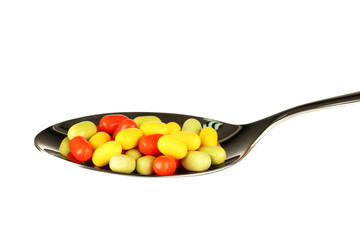 colorful pills on spoon on white background close-up