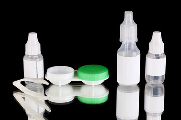 Eye drops and lenses on black background