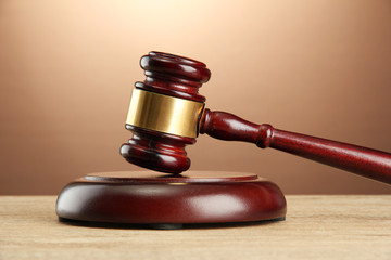 wooden gavel on wooden table, on brown background