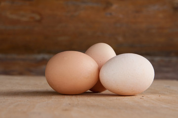 Three chicken eggs on old wooden board
