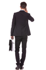 Obraz premium business man with briefcase and talking on his smartphone
