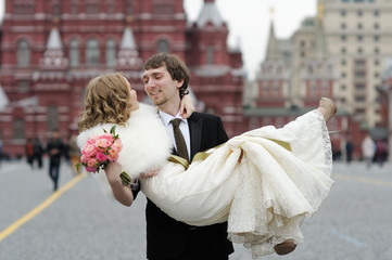 Happy groom holding young beautiful bride in his arms