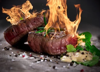 Photo sur Plexiglas Steakhouse Steaks de barbecue grillés avec des flammes de feu