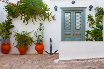 Door frame by pots and anchor in greek island