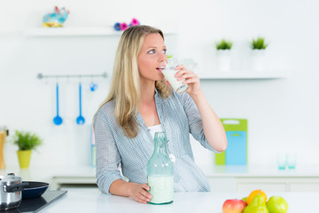 frau in de küche trinkt ein glas milch