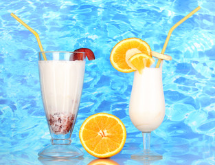 Delicious milk shake with fruit on table on blue sea background