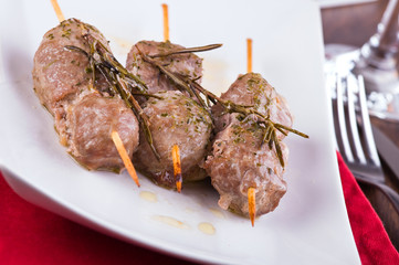 Meat skewers on white dish.